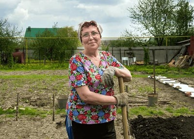 Femeie de vârstă mijlocie în grădină cu o lopată, demonstrând libertatea de mișcare și ameliorarea durerii articulare după utilizarea Aktibion.
